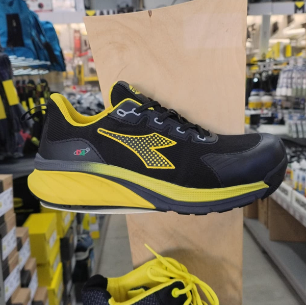 Scarpa da ginnastica nera e gialla esposta su uno scaffale di un negozio.