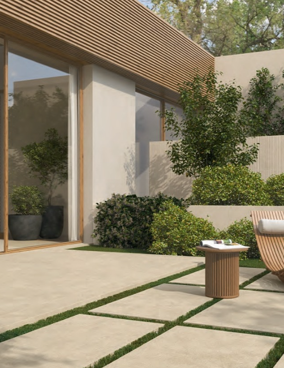 Patio moderno con pavimentazione in pietra, piante in vaso e pergolato in legno accanto a grandi porte finestre.