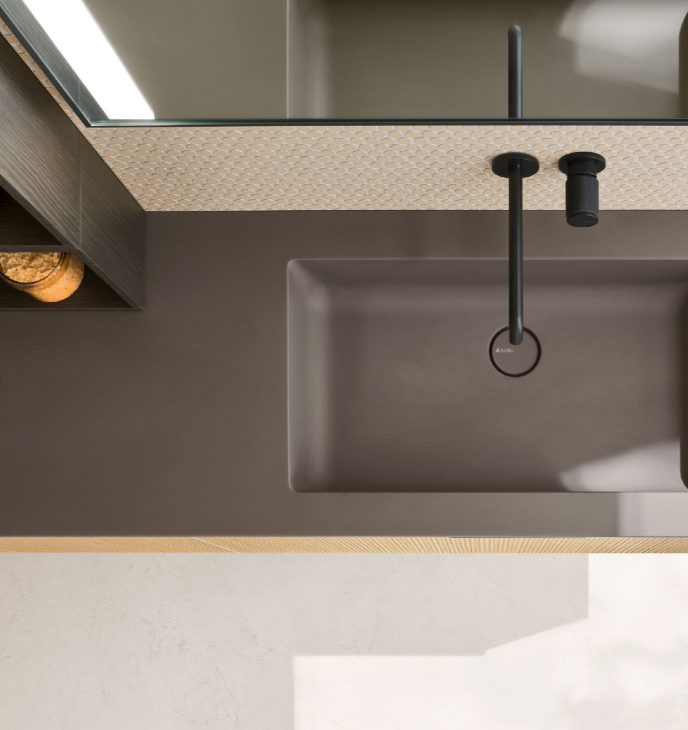 Vista dall'alto di un moderno lavabo da bagno con rubinetto nero opaco e piano d'appoggio neutro.