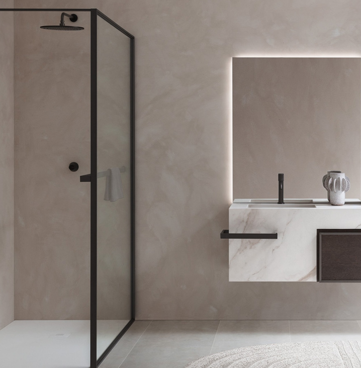 Bagno moderno con box doccia in vetro e lavabo a parete nei toni del beige.