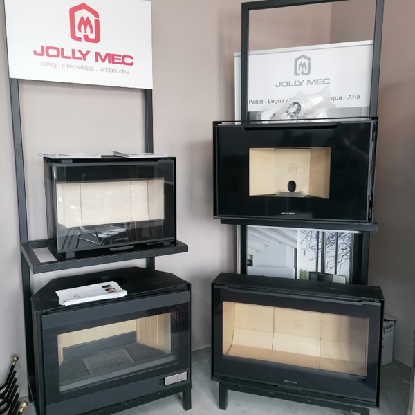Espositore per caminetto elettrico JOLLY MEC di colore nero con quattro inserti frontali in vetro, in una sala espositiva.
