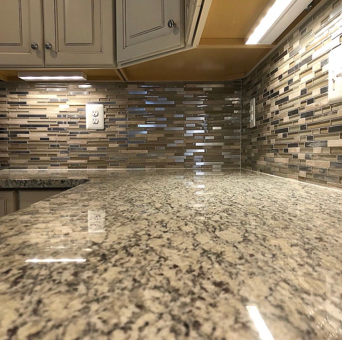 Close-up of kitchen countertop with granite surface and tile backsplash.