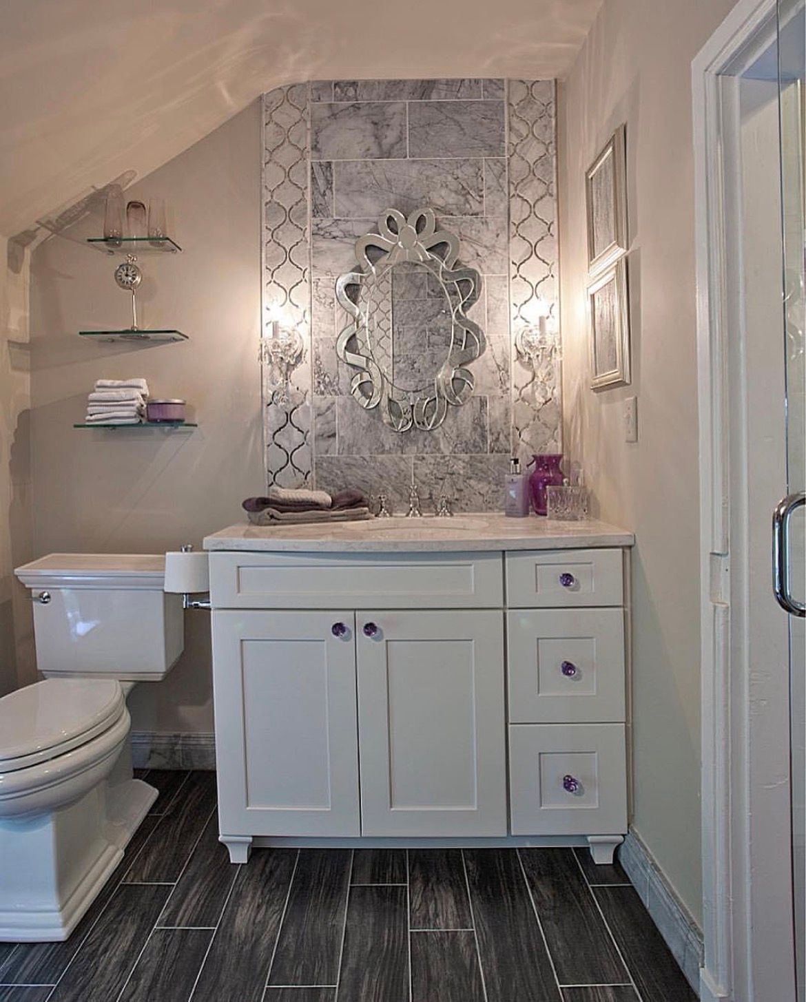 Bathroom with white vanity, decorative mirror, and gray tile floor.