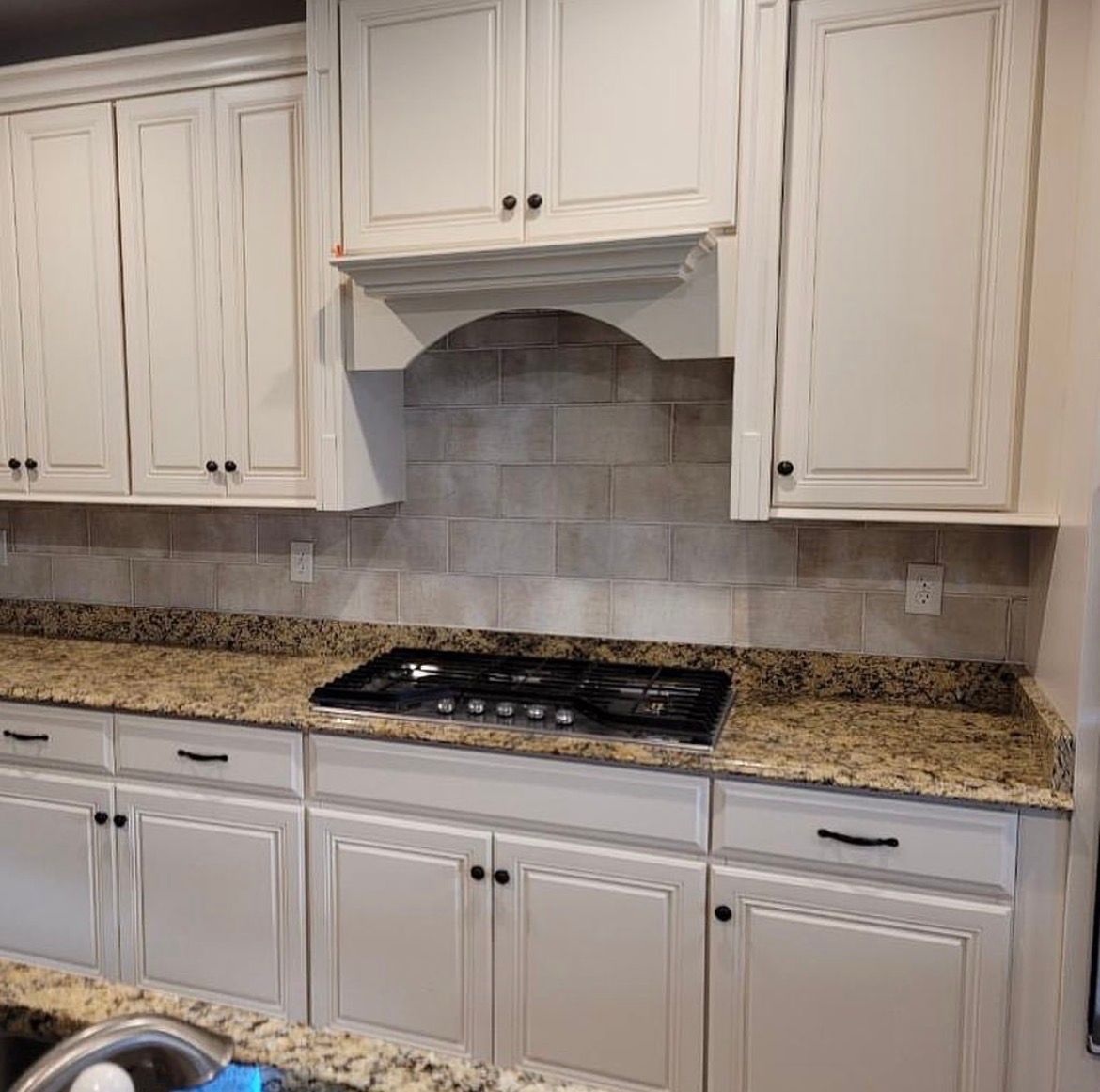 Cream-colored kitchen cabinets, granite countertops, gas stovetop, and tiled backsplash.