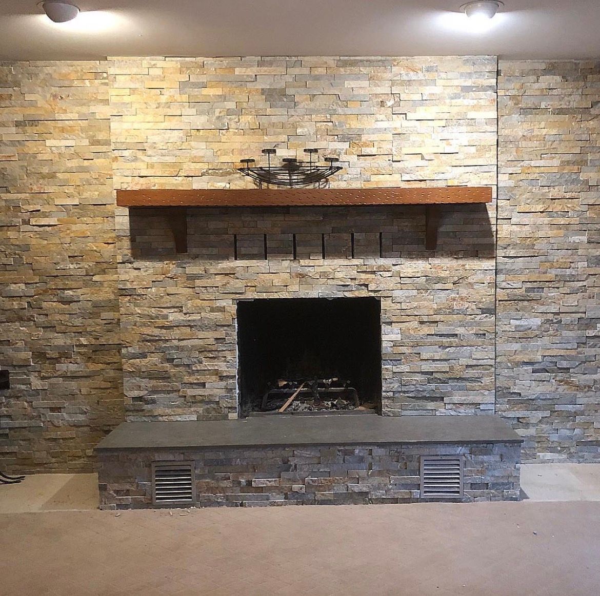 Fireplace with a stone facade, wooden mantle, and stone hearth.