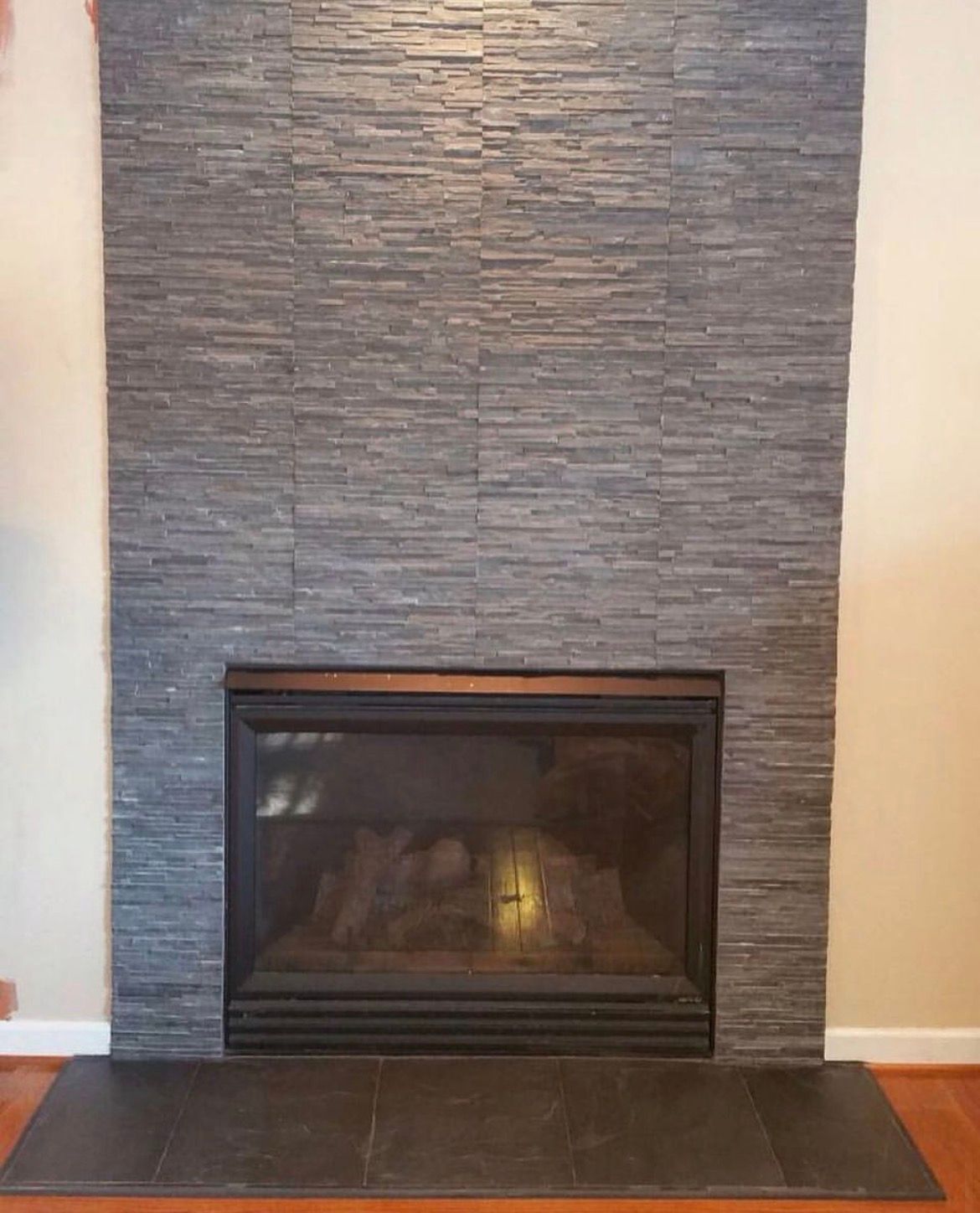 Fireplace with dark gray stone tile surround and black firebox.