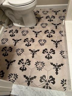 Black and white patterned hexagonal tile bathroom floor around a white toilet.
