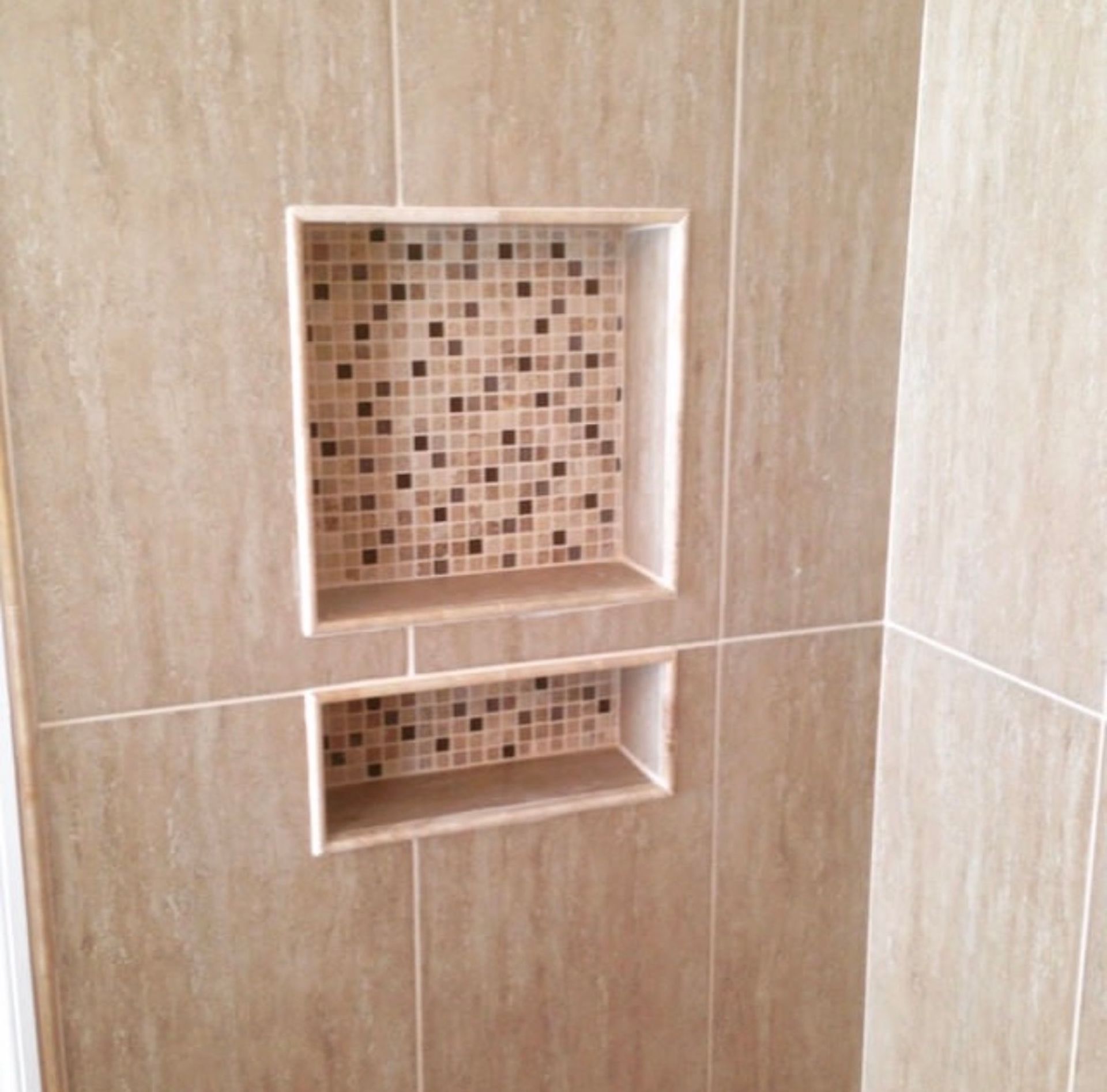 Two tile-lined shower niches.  Main tile is beige; interiors are mosaic brown and tan.