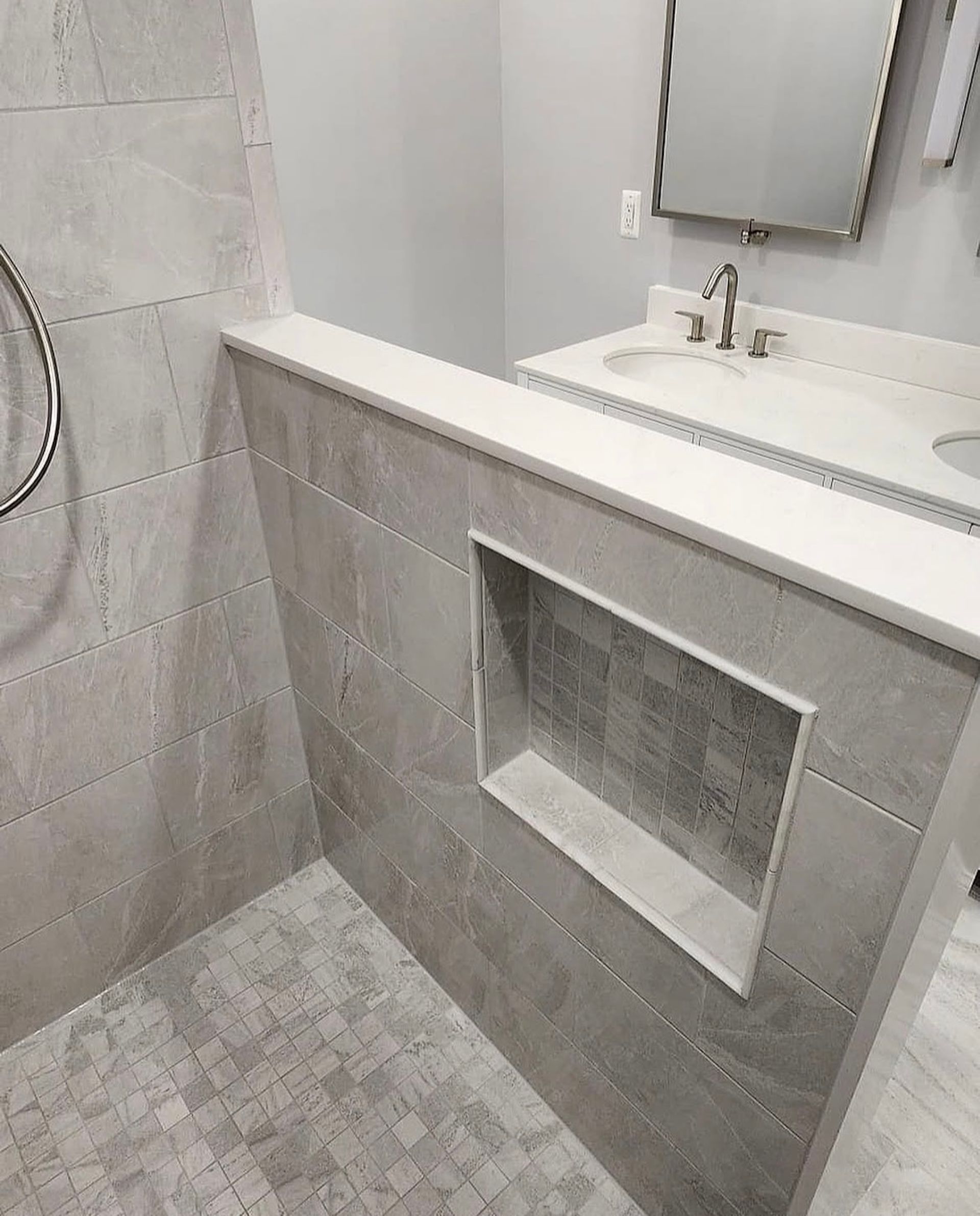 Bathroom with gray tiled shower and vanity with sink and mirror.