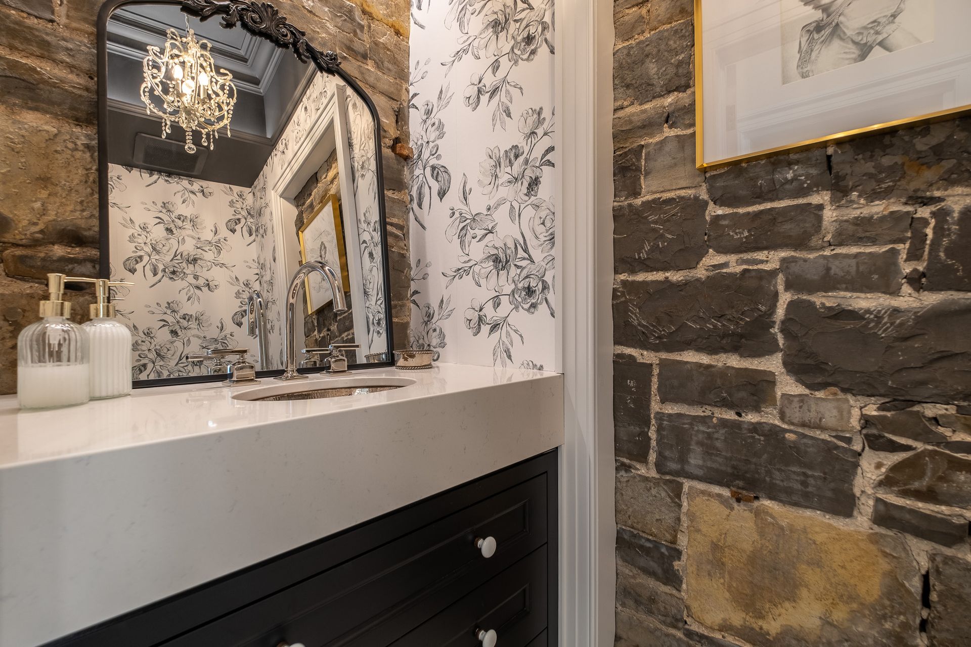 A bathroom with a stone wall, a sink and a mirror.