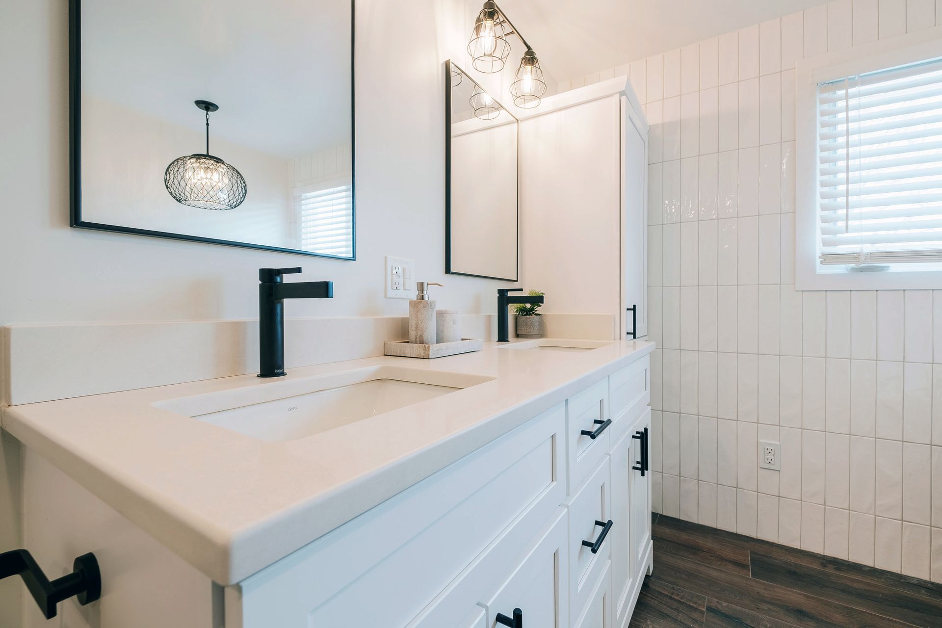 A bathroom with two sinks and two mirrors`.