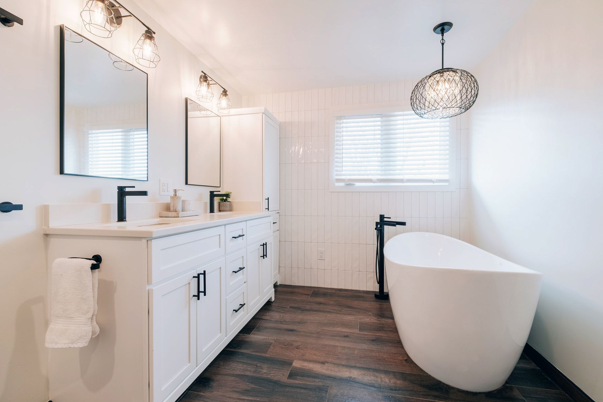 A bathroom with a tub, sink, mirror and toilet.