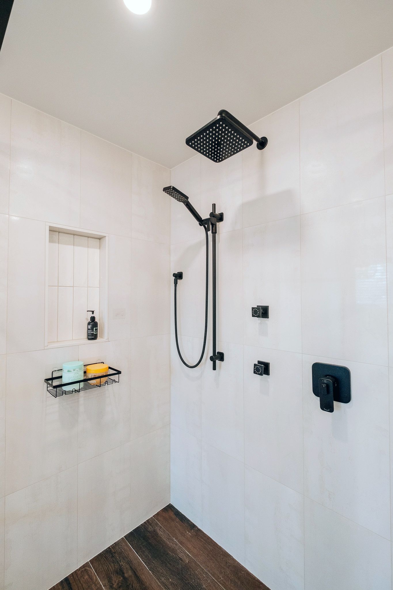 A shower with a black shower head.