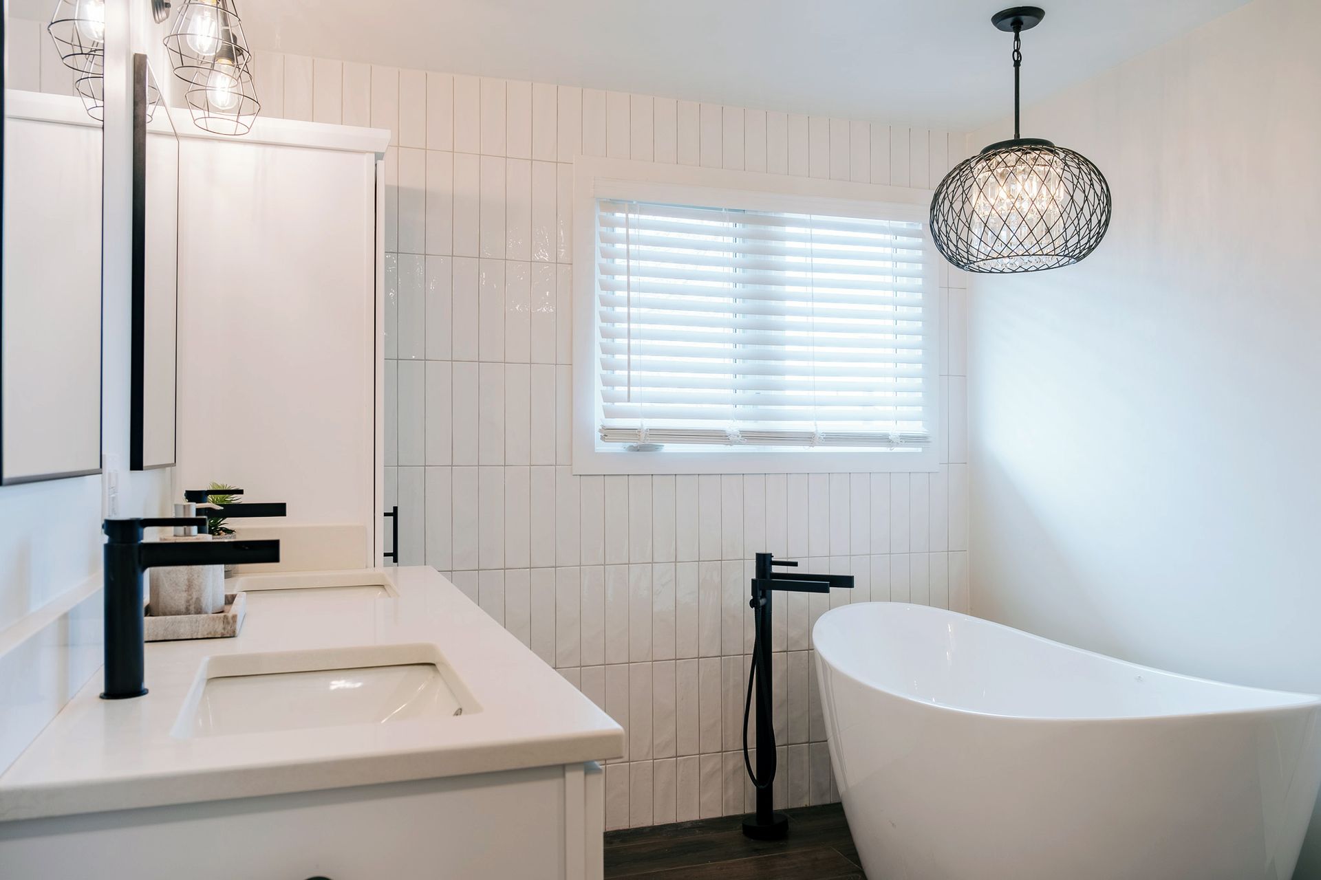 A bathroom with two sinks , a tub and a window.