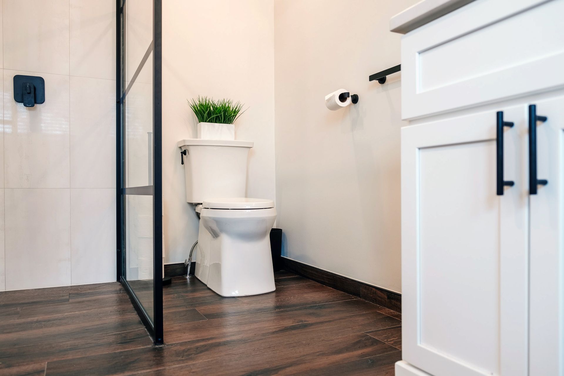 A bathroom with a toilet, sink, and walk in shower.