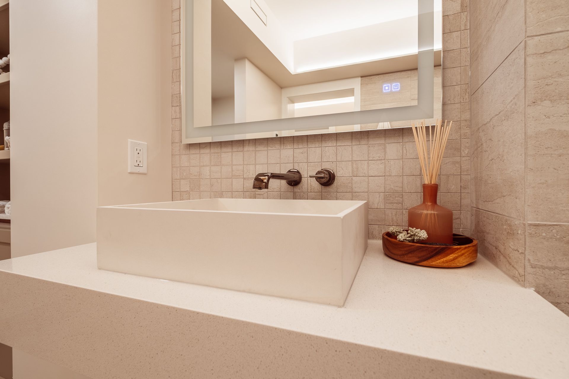 A bathroom with a sink, mirror and vase.
