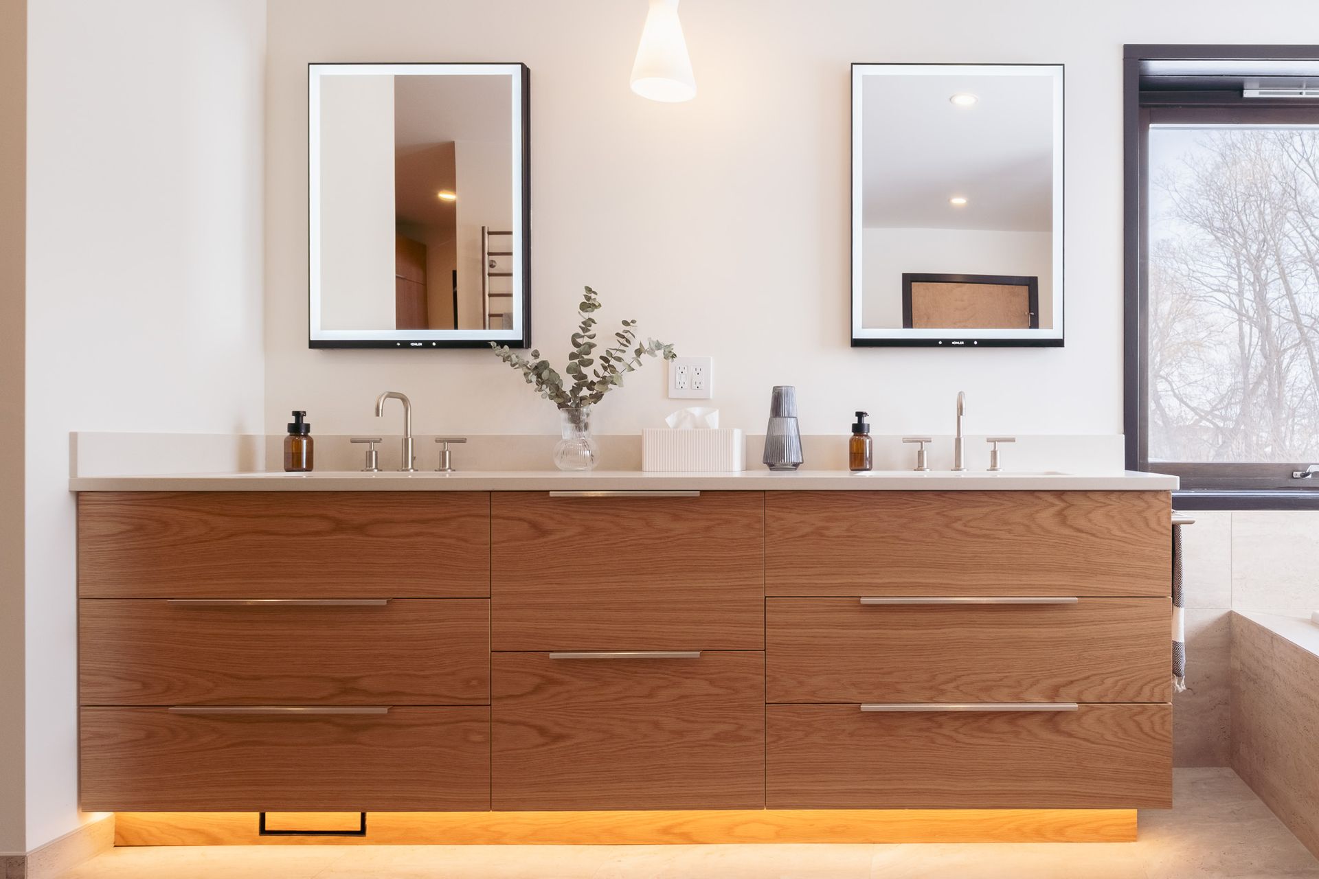 A bathroom with two sinks, two mirrors and a window.