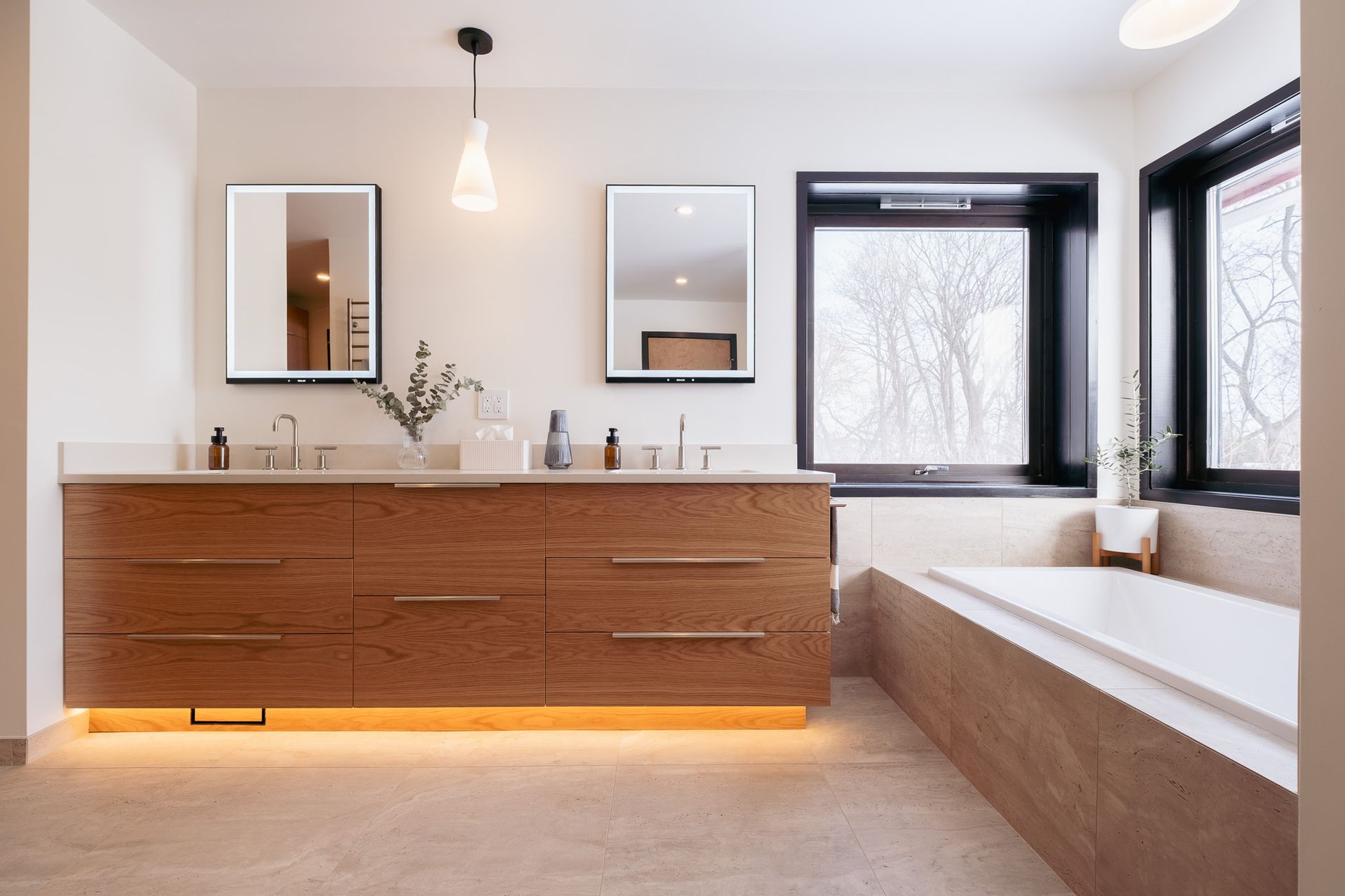 A bathroom with two sinks, two mirrors and a tub.