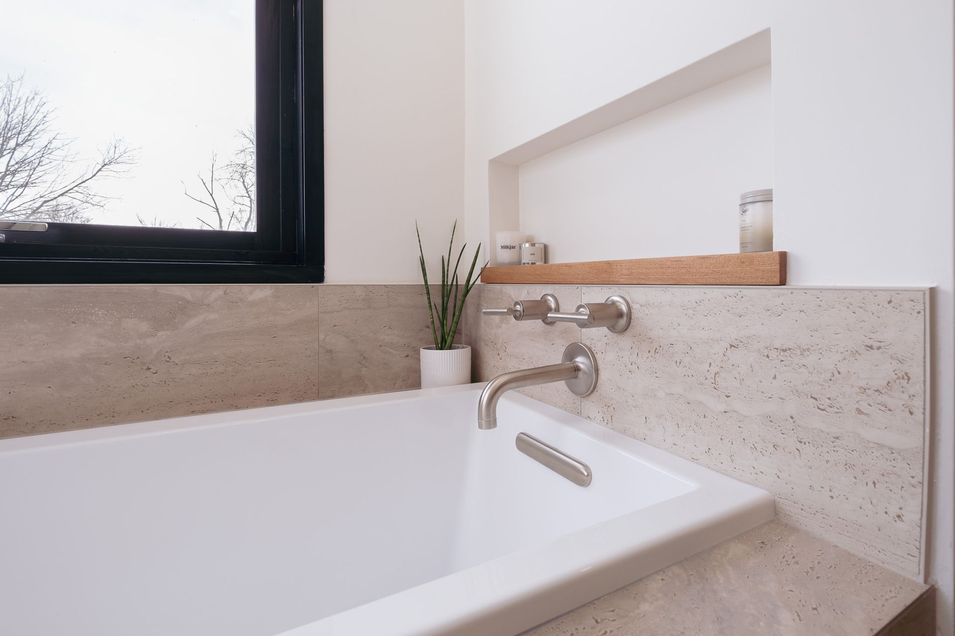 A bathtub in a bathroom next to a window.
