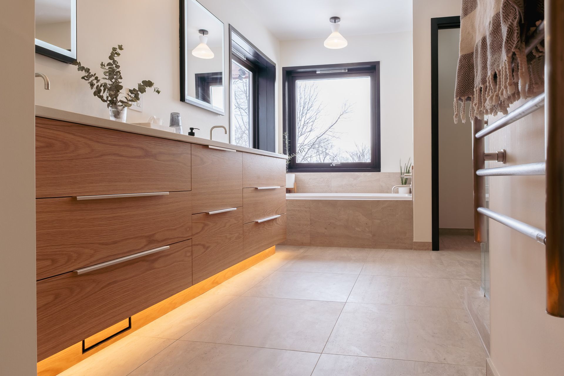 A bathroom with two sinks, a tub, a mirror and a window.
