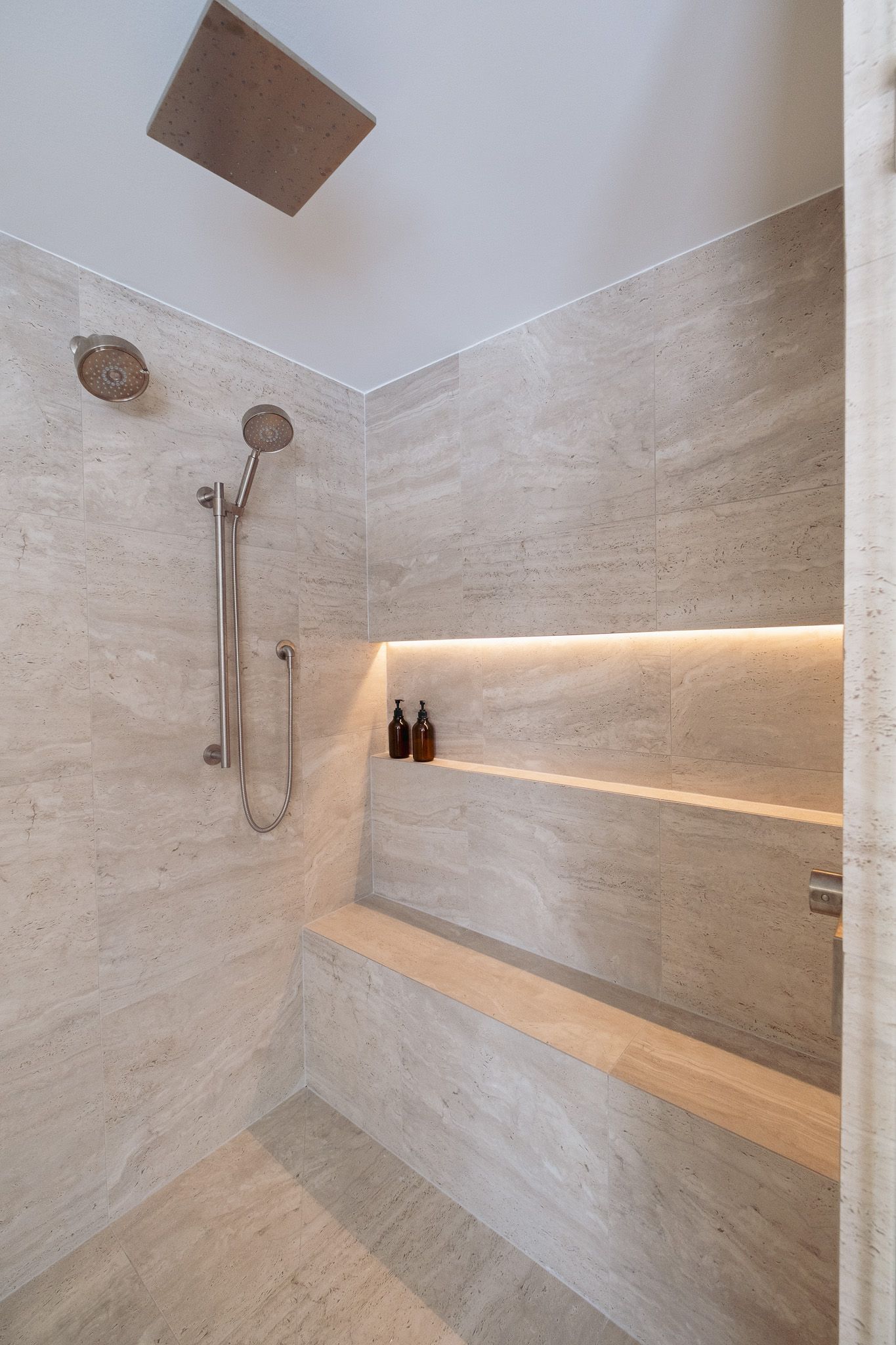 A bathroom with a walk in shower and a shelf.