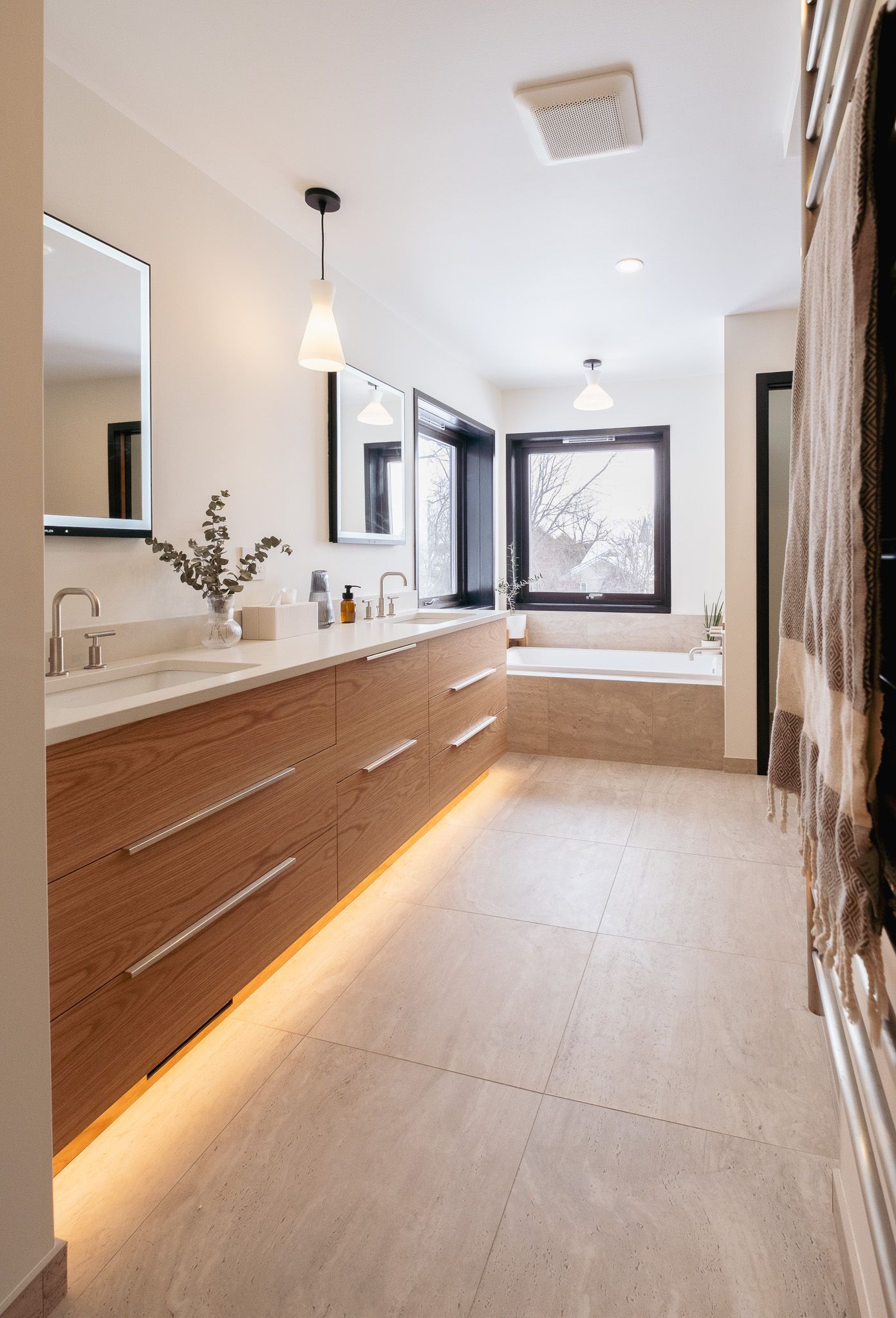 A bathroom with two sinks, a tub and a mirror.