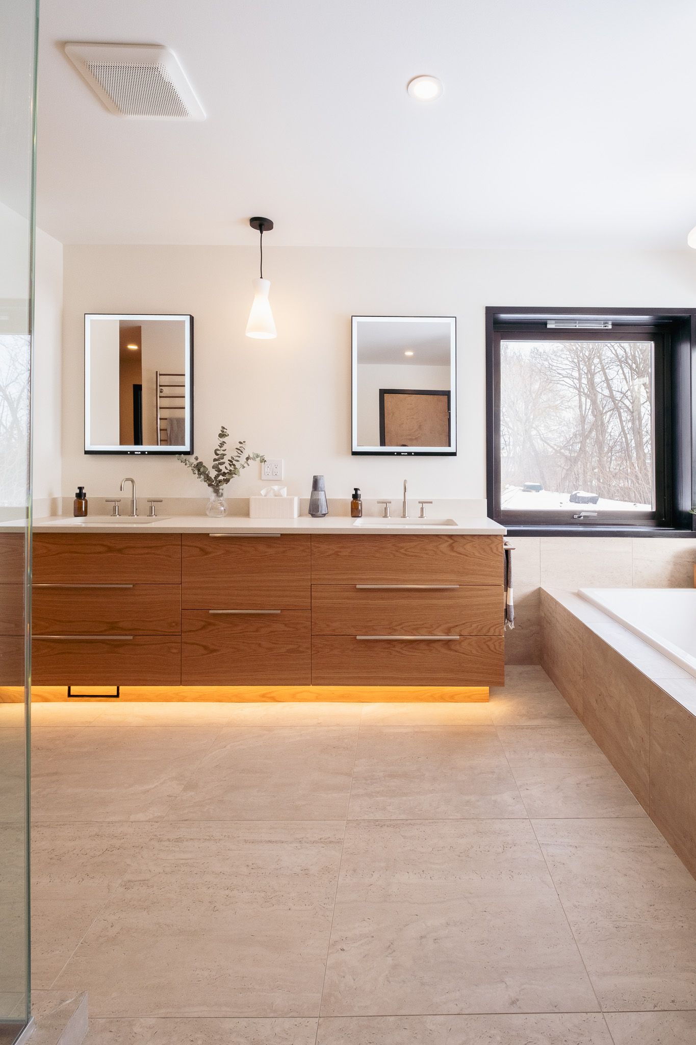 A bathroom with two sinks, two mirrors and a bathtub.
