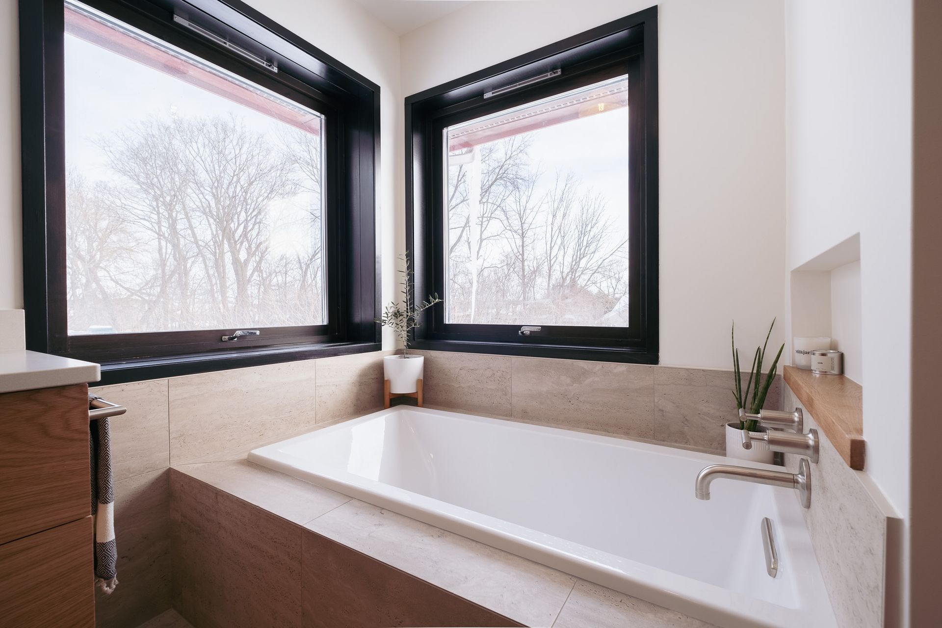 A bathroom with a bathtub and two windows.
