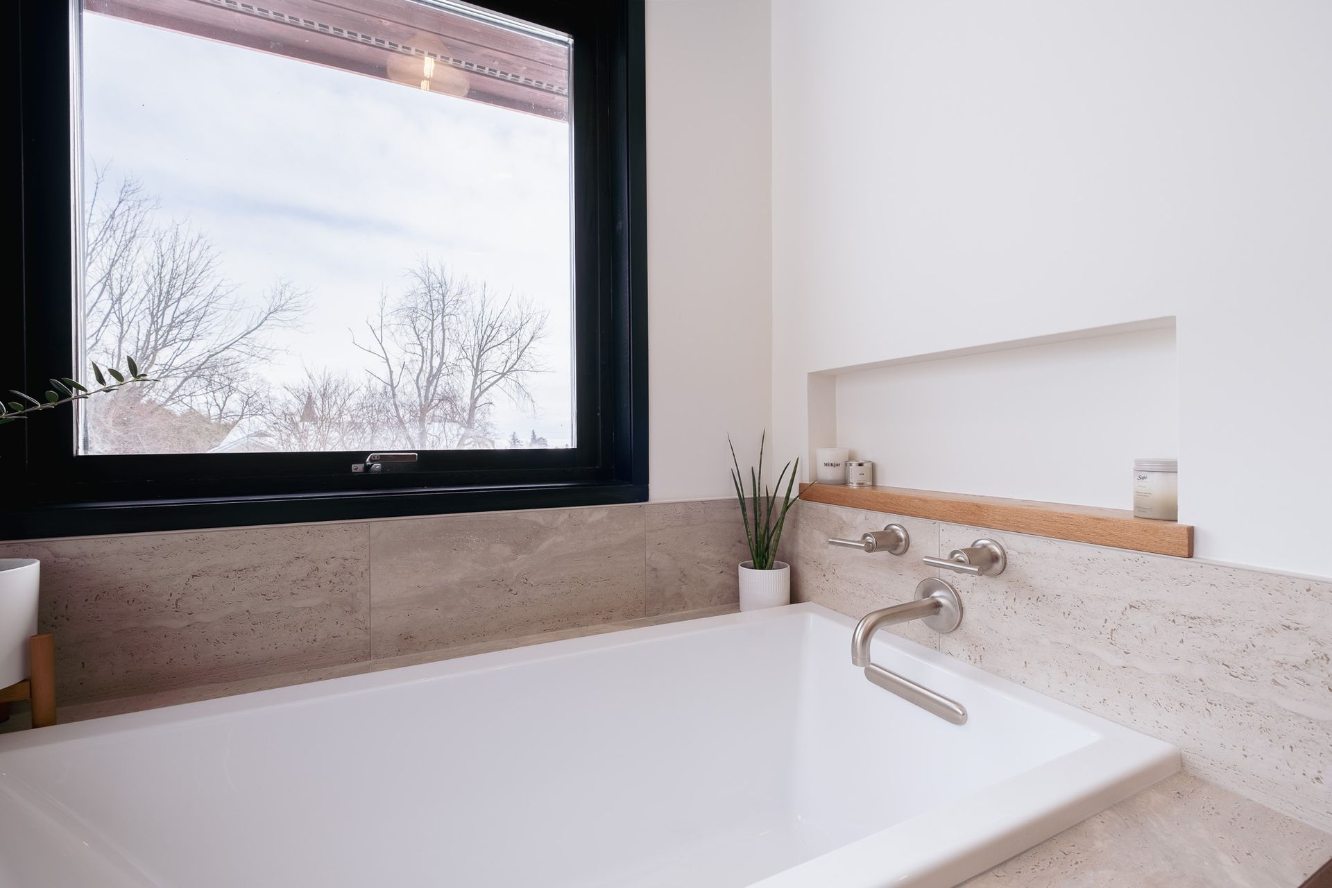 A bathtub in a bathroom next to a window.