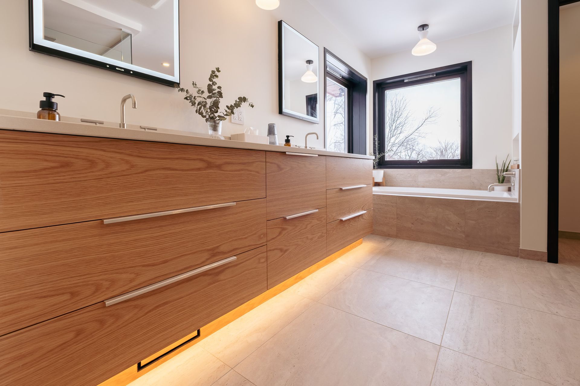 A bathroom with two sinks, a tub, a mirror and a window.