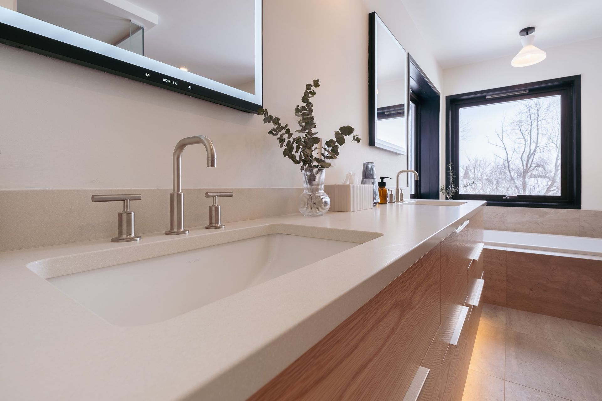 A bathroom with two sinks, a mirror and a window.