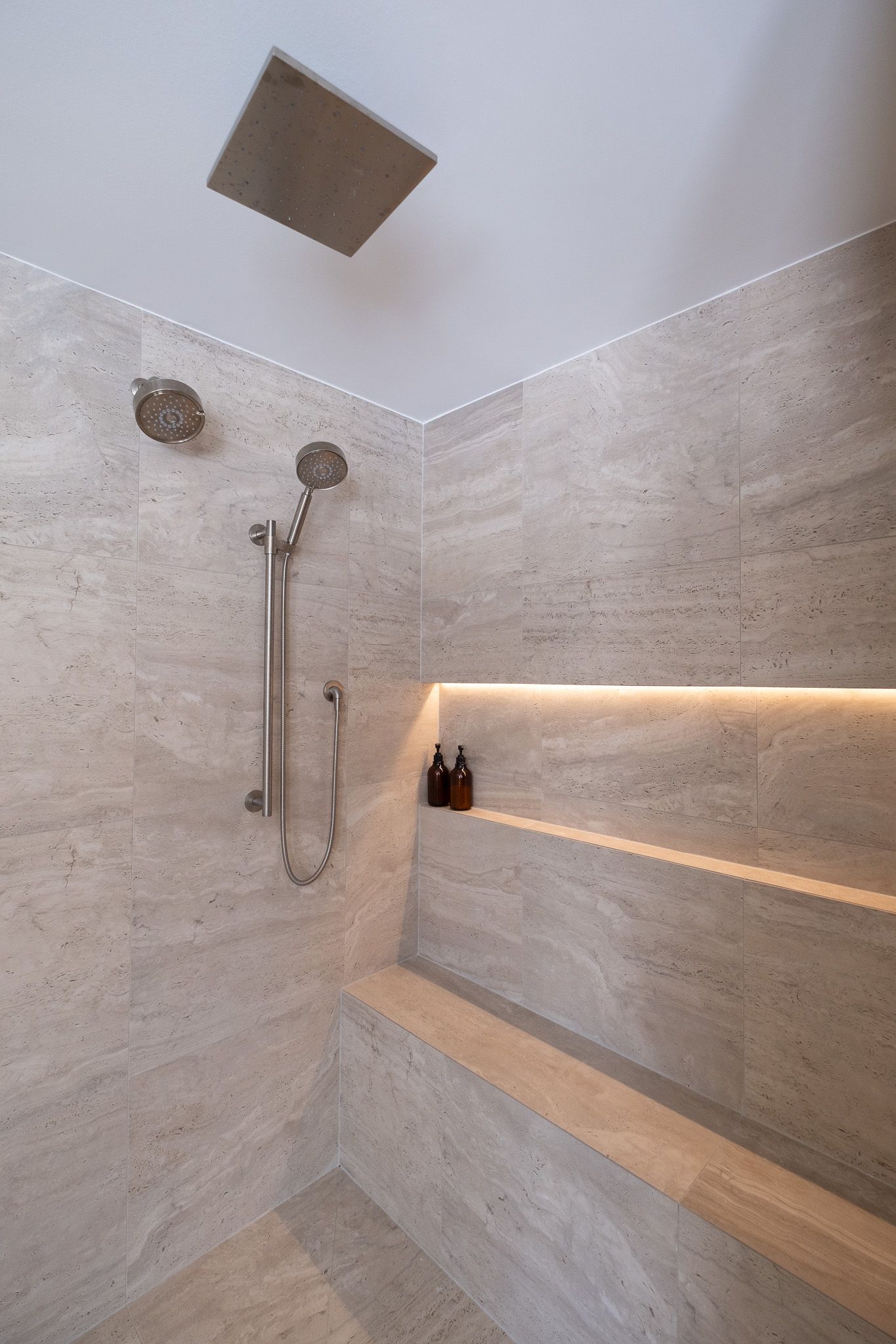A bathroom with a shower head and a shelf.