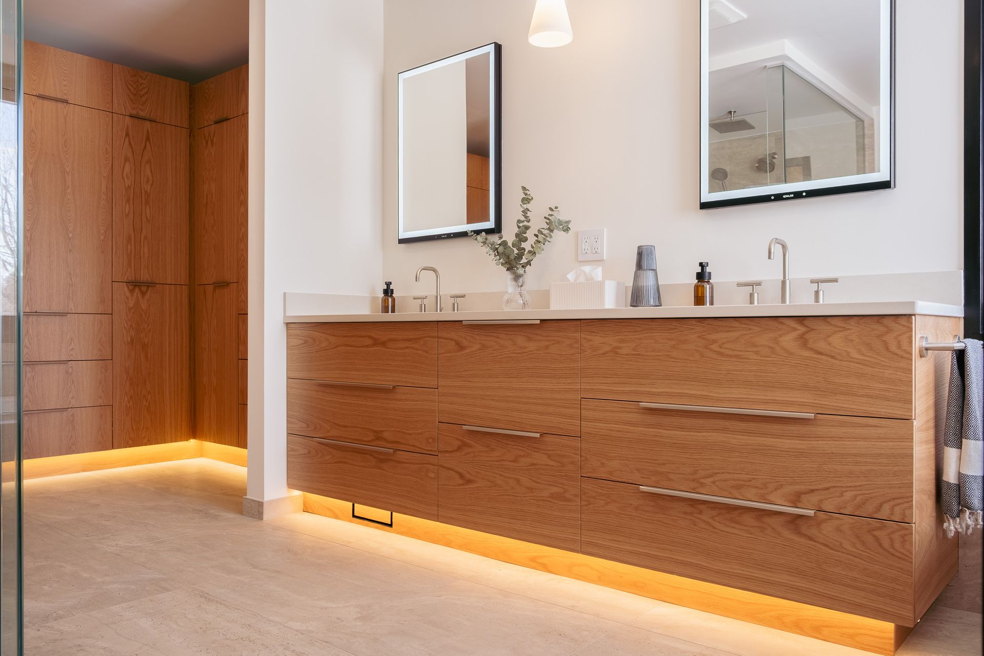 A bathroom with two sinks, a mirror and a walk in shower.