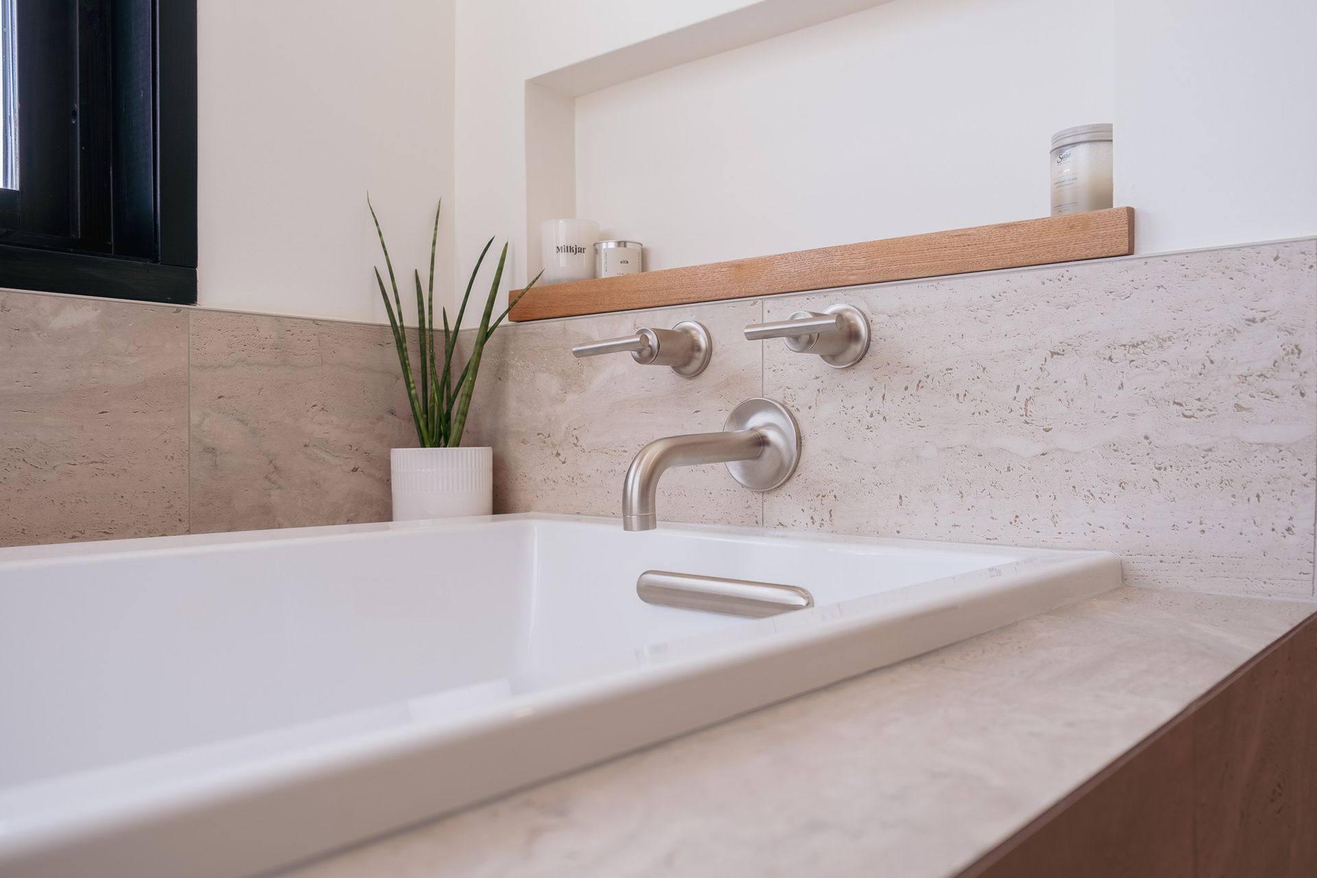 A bathroom with a bathtub and a plant on the counter.