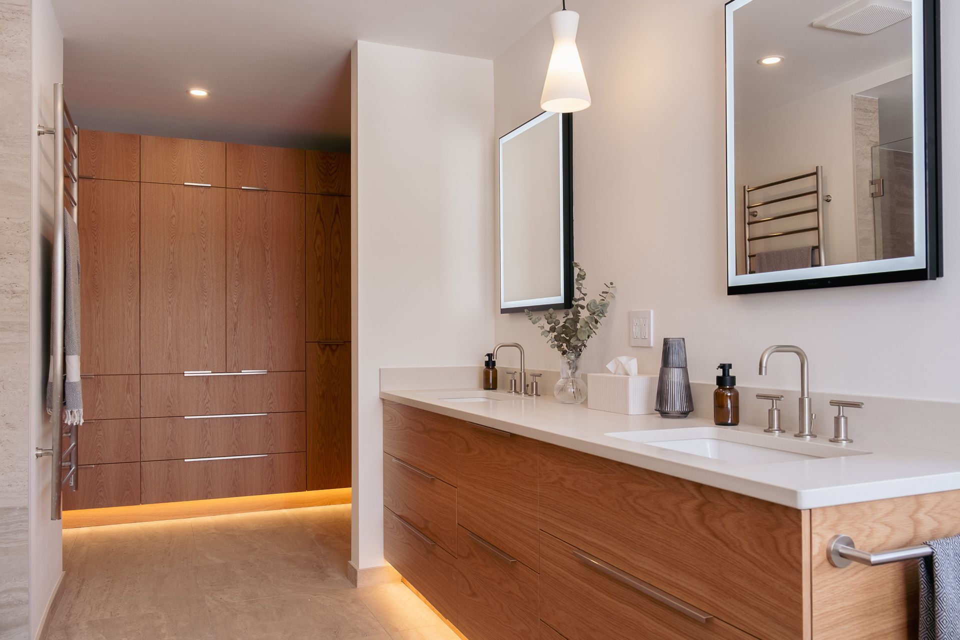 A bathroom with two sinks, a mirror and a closet.