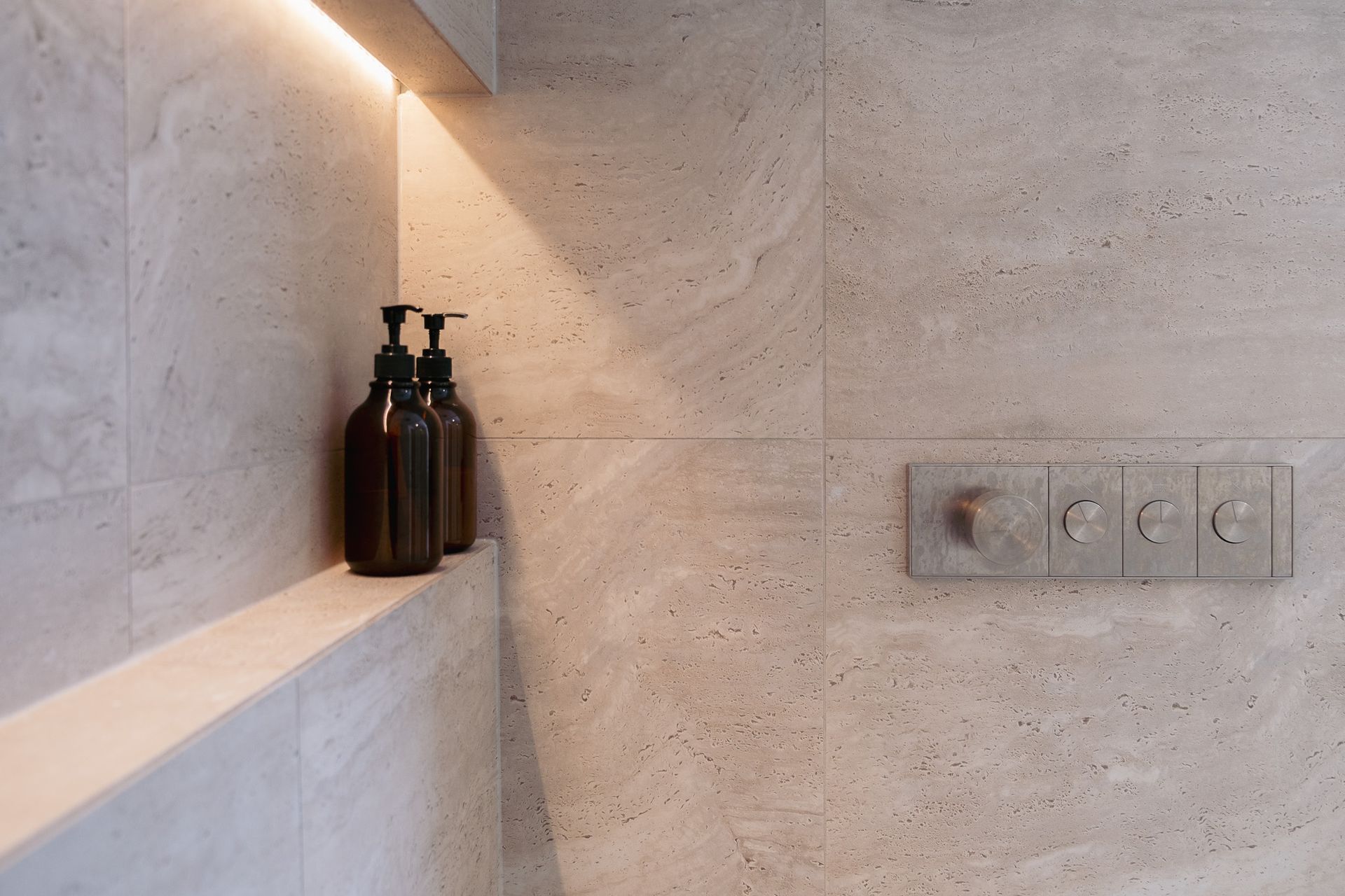 Two bottles sitting on a shelf in a bathroom.