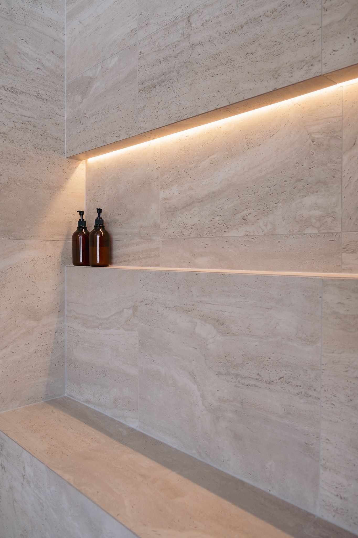 Two bottles sitting on a shelf in a shower.