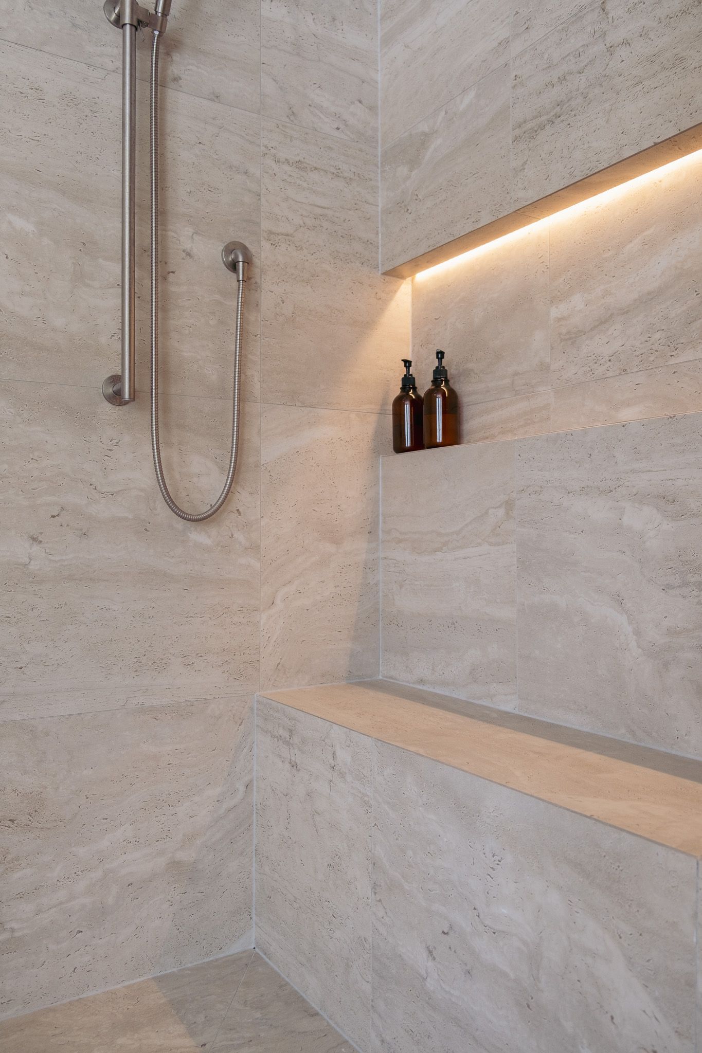 A shower and two bottles on the wall.