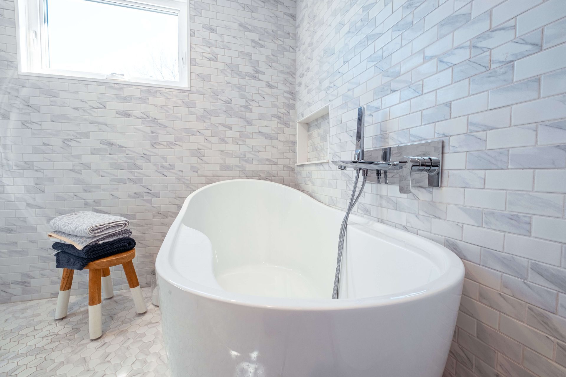 There is a bathtub in the bathroom with a stool next to it.