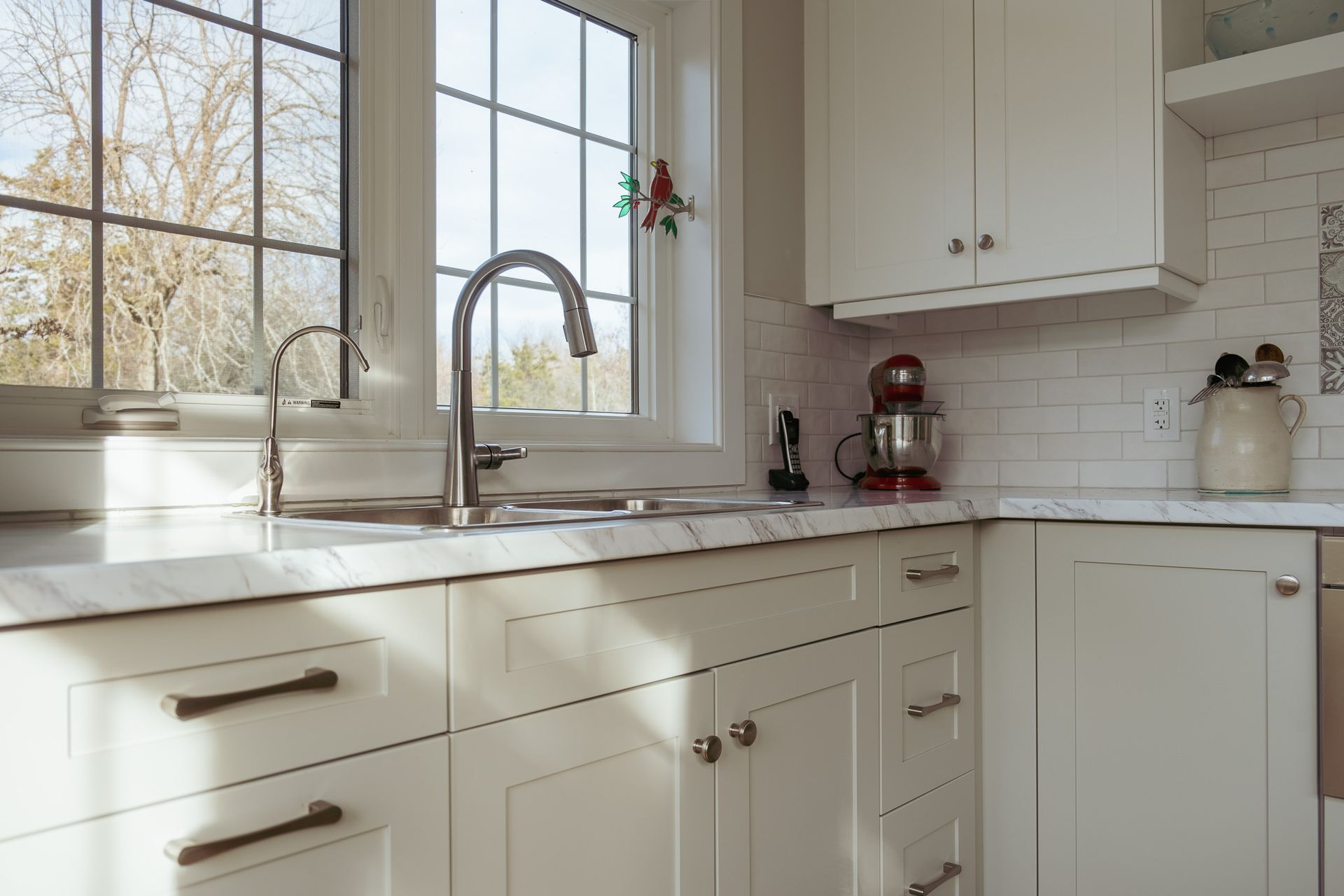 A kitchen with white cabinets, a sink, and a window.