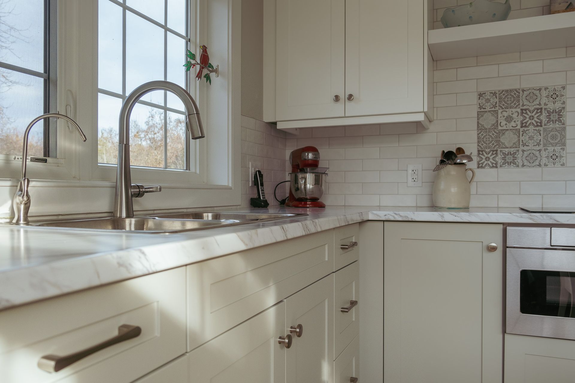 A kitchen with white cabinets, a sink, and a window.