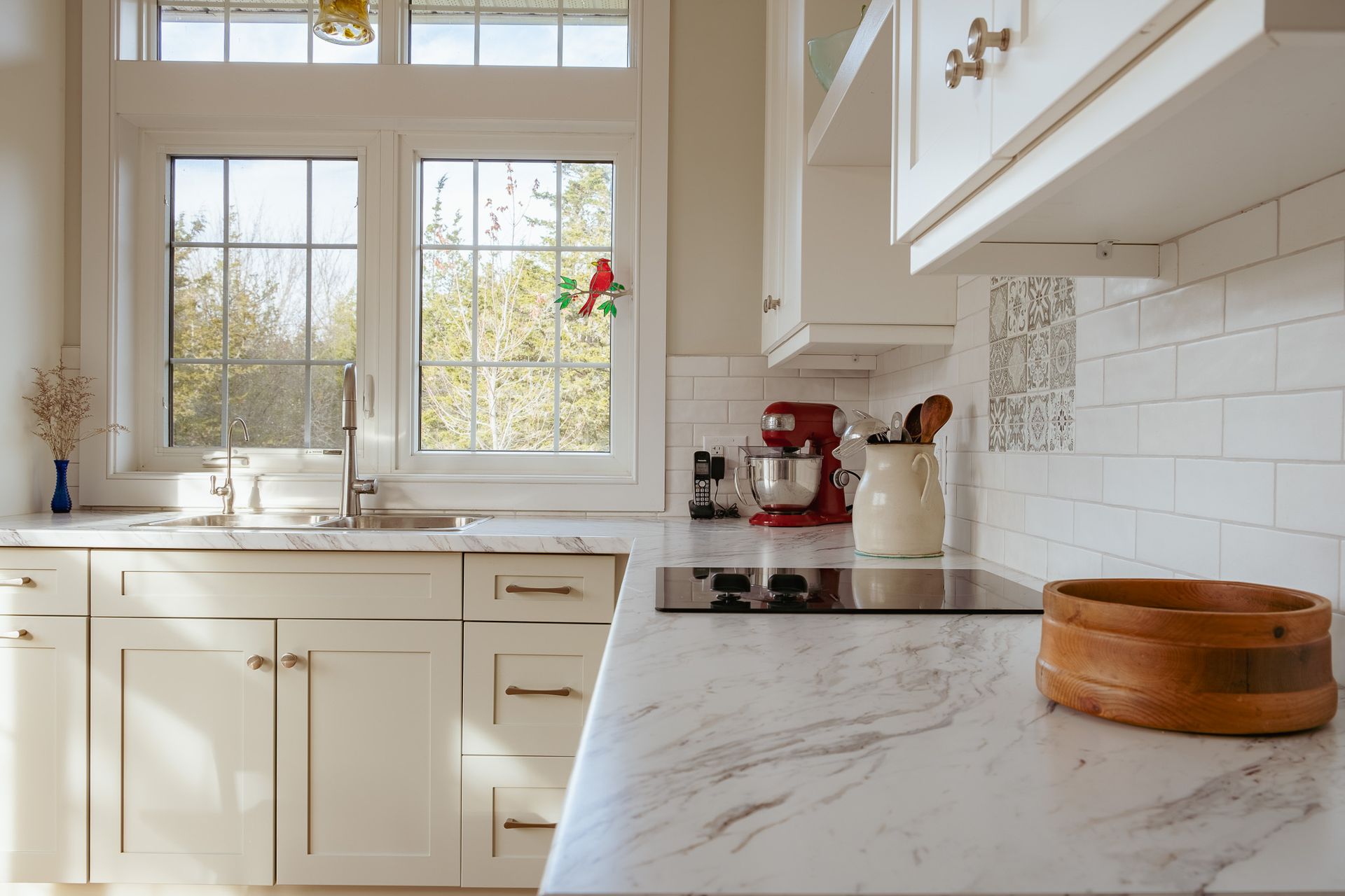 A kitchen with white cabinets, a stove top oven, a sink, and a window.