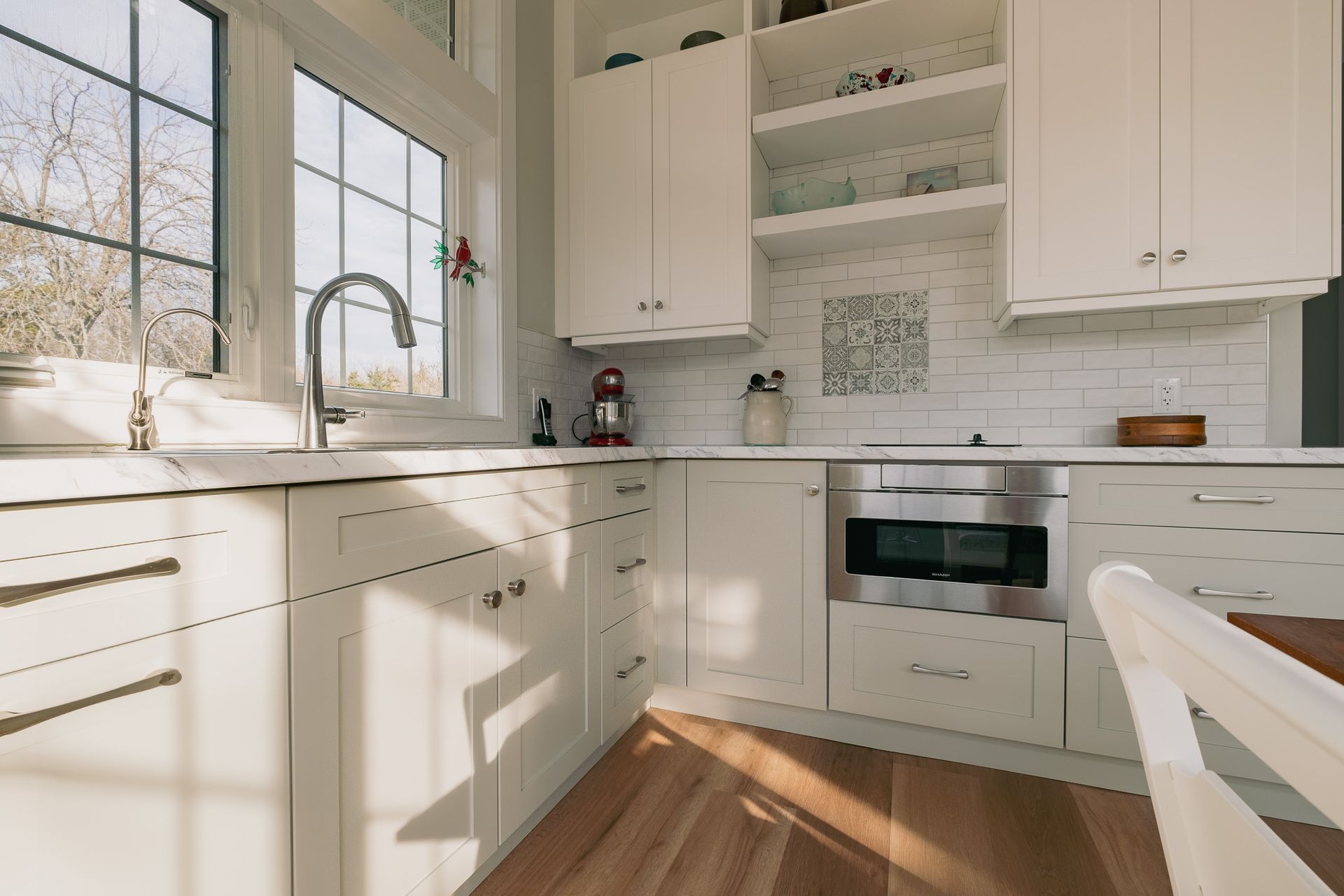 A kitchen with white cabinets, stainless steel appliances, a sink, and a window.