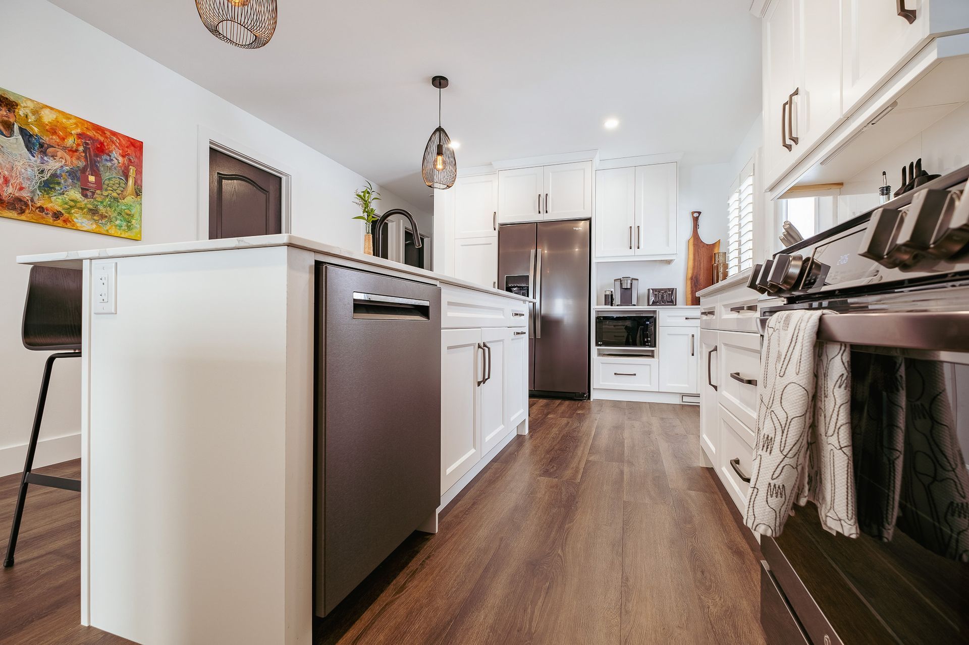 A kitchen with white cabinets, stainless steel appliances, and a large island.