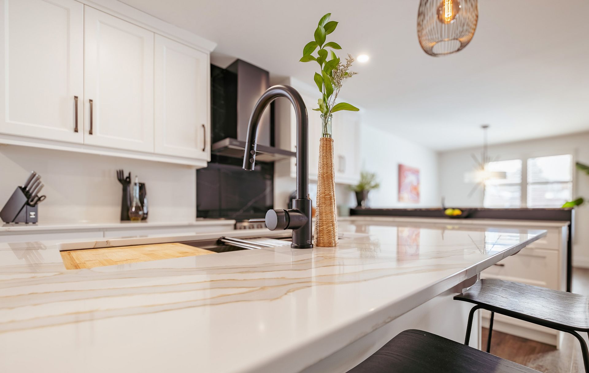 A kitchen with white cabinets, marble counter tops, a sink and a faucet.