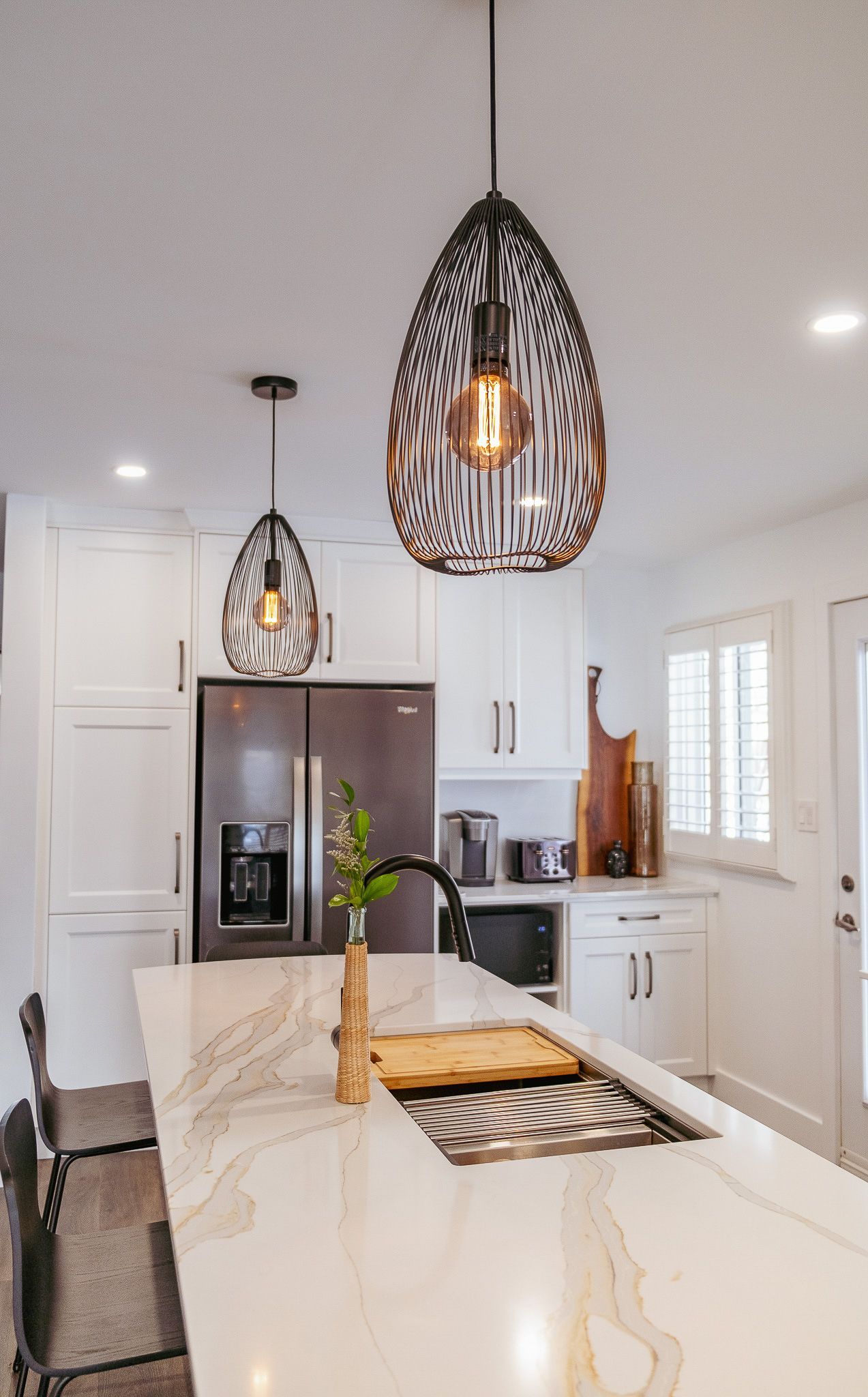 A kitchen with white cabinets, a sink, and a refrigerator.