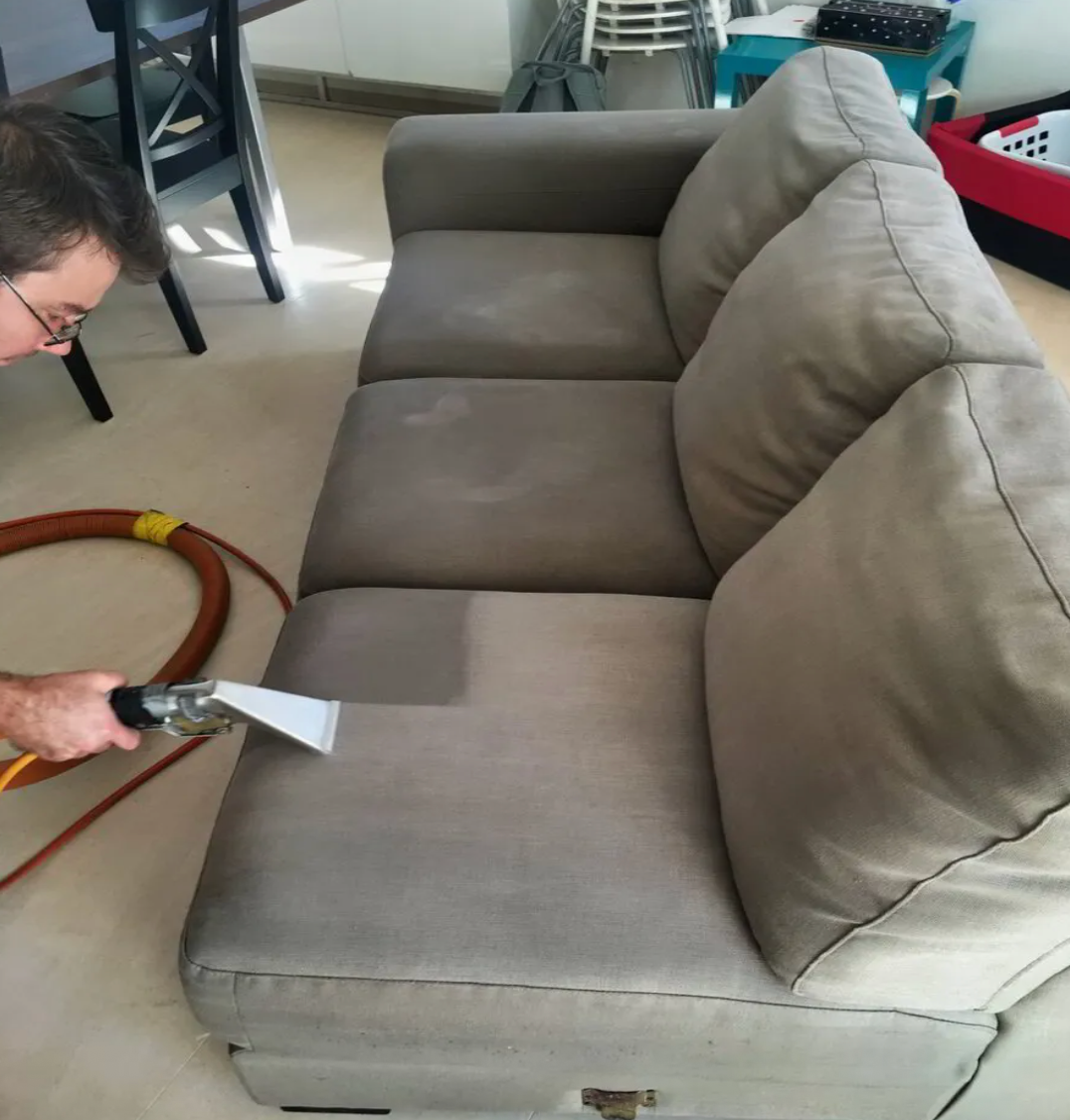 A Person is Cleaning a Grey Couch — Carpet Pro Care in Goonellabah, NSW