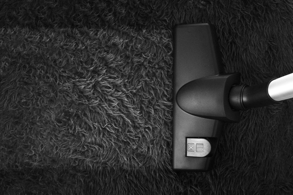 A Black and White Photo of a Vacuum Cleaner Cleaning a Black Carpet — Carpet Pro Care in Casino, NSW