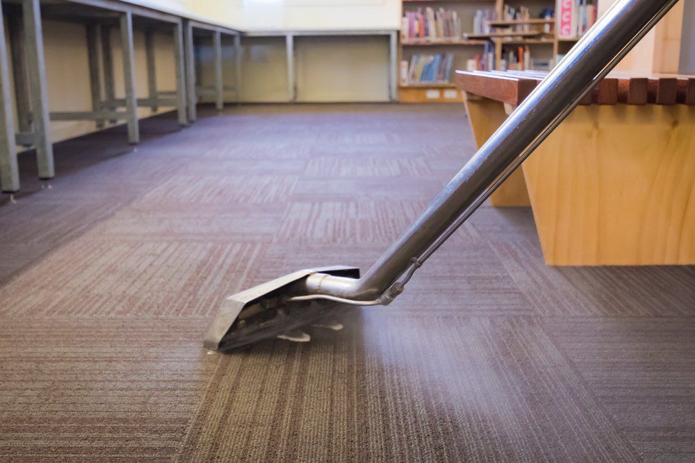 A Vacuum Cleaner is Cleaning a Carpeted Floor in a Library — Carpet Pro Care in Lismore, NSW