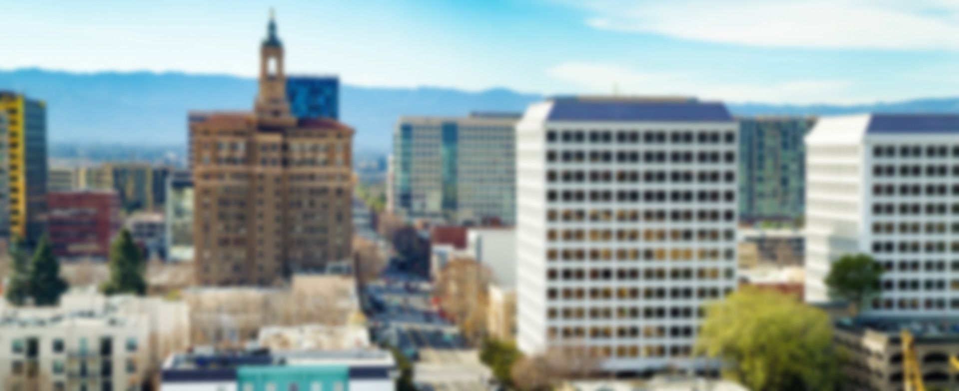 Downtown skyline with tall office buildings and a clock tower under a blue sky.
